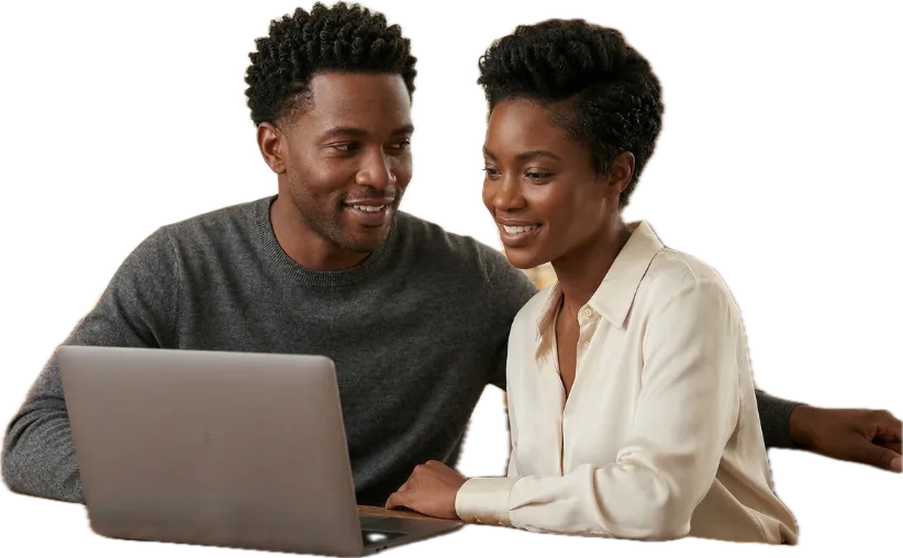 Two partners smiling at a laptop at their kitchen table
